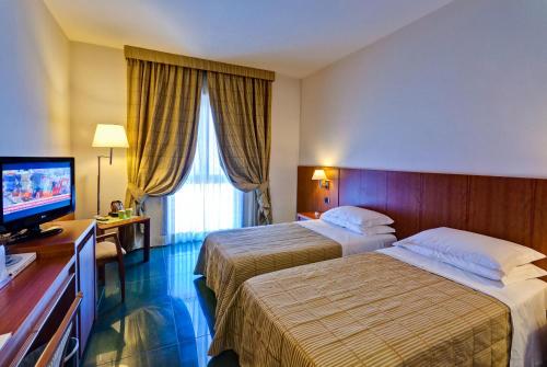 バロニッシにあるHotel Dei Principatiのベッド2台、薄型テレビが備わるホテルルームです。