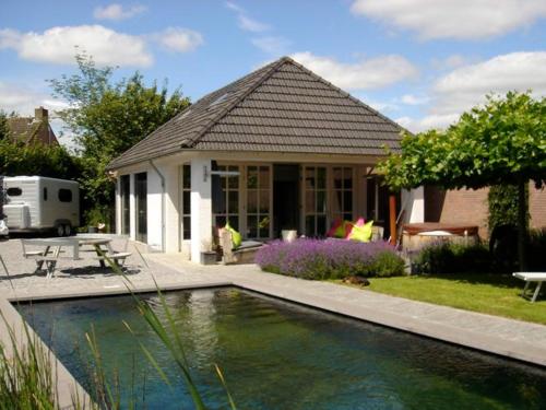 a house with a swimming pool in front of a house at Gardenhouse with private jacuzzi & private sauna in Teteringen