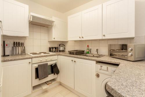 a white kitchen with white cabinets and appliances at Host & Stay - New Street Suite in Worcester