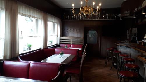 ein Restaurant mit einer roten Couch sowie einem Tisch und Stühlen in der Unterkunft Gasthof Sommer in Bösel