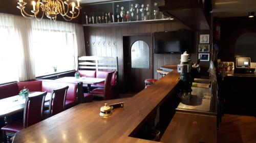 a dining room with a long wooden table and red chairs at Gasthof Sommer in Bösel