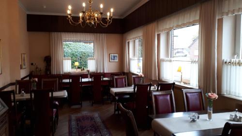 Gasthof Sommer في Bösel: غرفة طعام مع طاولات وكراسي ونوافذ