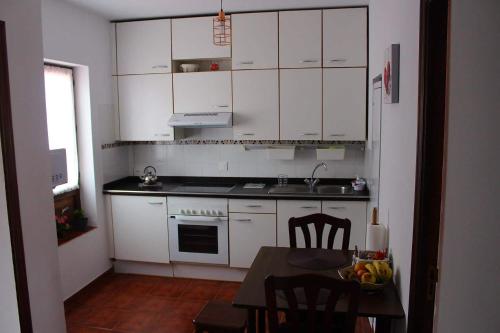 a kitchen with white cabinets and a table with chairs at MADESAIK in Breña Baja