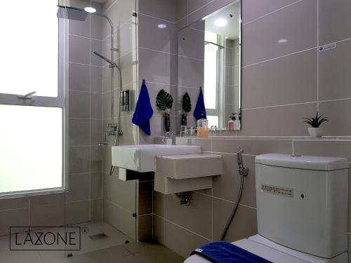 Un baño con lavabo, inodoro y espejo. en Sutera Avenue Kota Kinabalu By LAXZONE, en Sembulan
