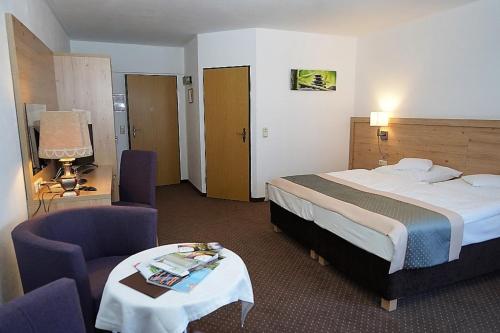 a hotel room with a bed and two chairs and a table at Land-gut-Hotel Zum alten Forsthaus - Aufladestation für Elektroautos in Hürtgenwald