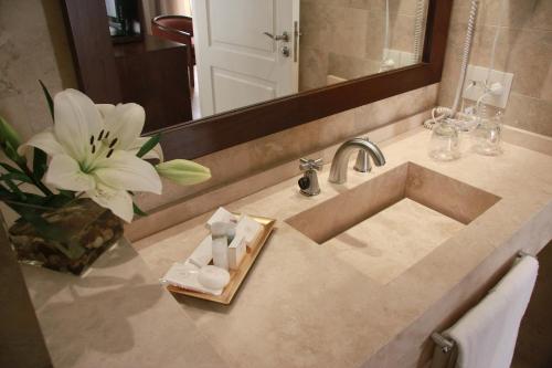 a bathroom sink with a flower and a mirror at Grand King Hotel in Buenos Aires