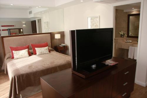 a flat screen tv sitting on top of a wooden stand at Grand King Hotel in Buenos Aires