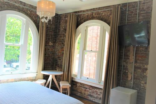 a bedroom with brick walls and a bed and two windows at Hotel Hale in Hot Springs