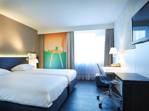 a hotel room with a bed and a desk at Postillion Hotel Dordrecht in Dordrecht