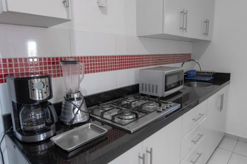 a kitchen counter with a stove and a microwave at Apartamentos Torre II Condominios - Pet Friendly in Mazatlán