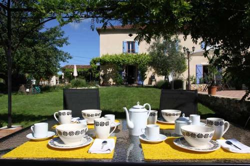 een tafel met bekers en schotels op een geel tafelkleed bij Au Mas du Soleil in Senouillac