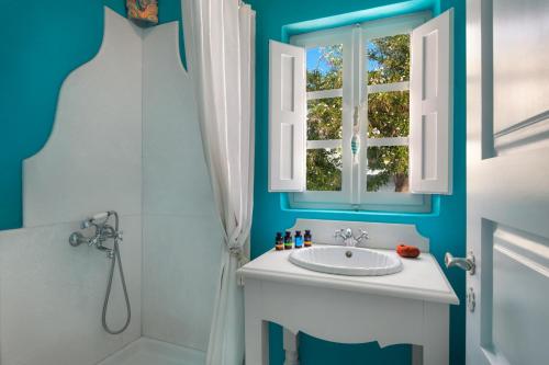 ein Bad mit einem Waschbecken, einer Dusche und einem Fenster in der Unterkunft Barocco Bello Studio in Fira