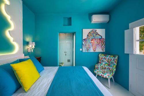 ein blaues Schlafzimmer mit einem Bett und einem Stuhl in der Unterkunft Barocco Bello Studio in Fira