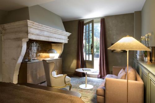 a living room with a bed and a fireplace at Baumanière - Les Baux de Provence in Les Baux-de-Provence
