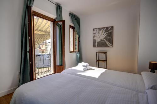 a bedroom with a white bed and a window at Apartamentos Setas Center in Seville