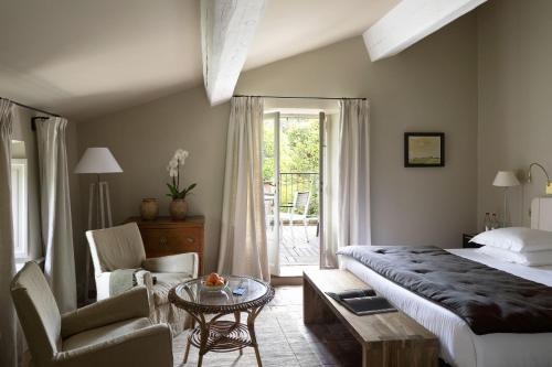 a bedroom with a bed and a chair and a table at Baumanière - Les Baux de Provence in Les Baux-de-Provence