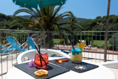 dos bebidas sentadas en una mesa junto a una piscina en Hotel Le Acacie en Capoliveri