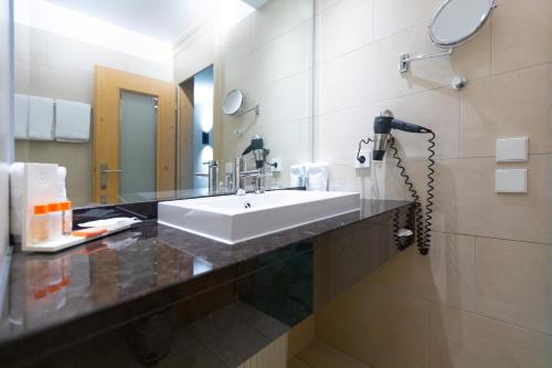 a bathroom with a white sink and a mirror at Olymp Munich in Eching