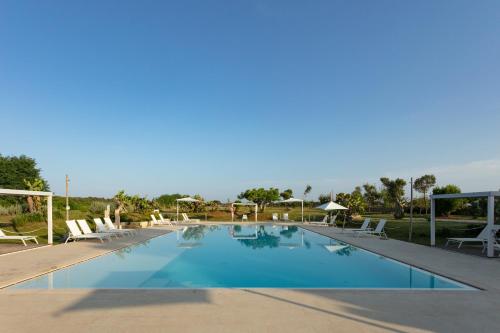 a large swimming pool with lounge chairs and umbrellas at Masseria Mongiò dell'Elefante in Otranto