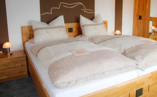 a large bed in a bedroom with two night stands at 3 Sterne Ferienwohnung Pape in Schmallenberg