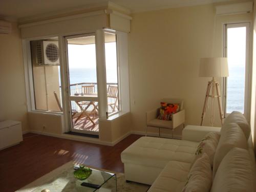 a living room with a couch and a view of the ocean at Listen the sound of the Sea - The Sunset of your Dreams in Funchal