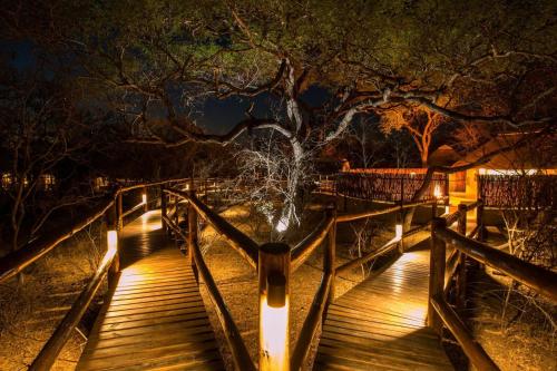 a wooden bridge over a river at night at Vuyani River Lodge in Hoedspruit