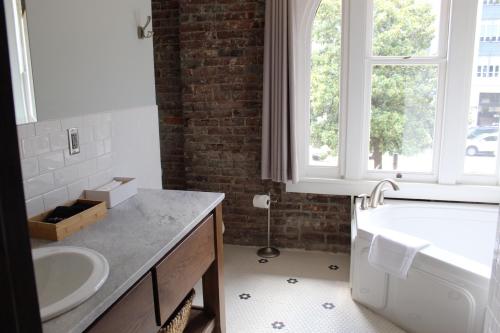 a bathroom with a sink and a tub and a window at Hotel Hale in Hot Springs