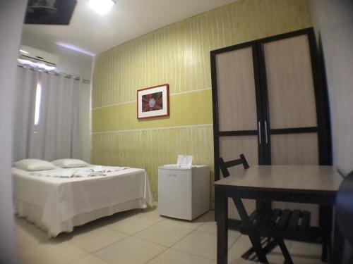 a bedroom with a bed and a table and a desk at Hotel Pousada Calliandra in Bonito