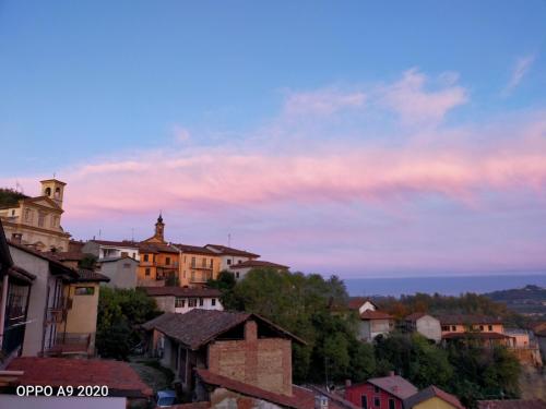 a group of buildings on a hill with a sunset at B&B Madonna degli Airali in Vezza d'Alba