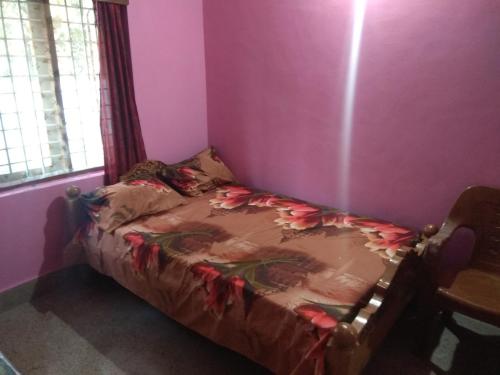 a small bed in a room with a pink wall at Dreams River view Homestay Coorg in Kushālnagar