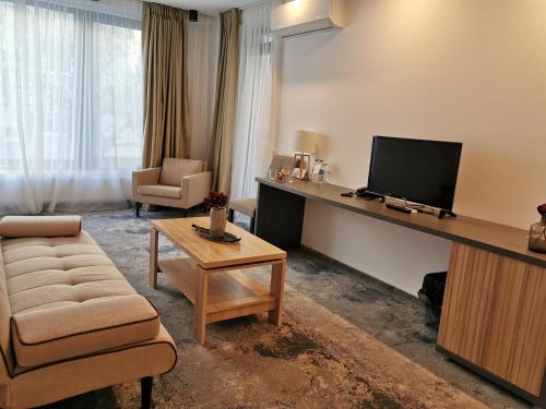 a living room with a television and a couch and a table at YMY Boutique Residence in Bucharest