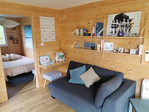 a living room with a couch and a bedroom at Chalet-studio Bien-Hetre in Fichous-Riumayou