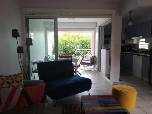salon z niebieską kanapą i kuchnią w obiekcie Beau T2 tout confort, résidentiel & calme w mieście Le Gosier