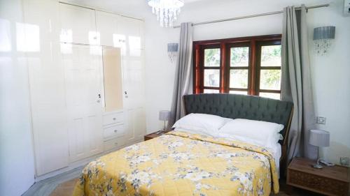 a bedroom with a bed with a yellow bedspread and a window at Ogumka, Self catering , Beoliere, Mahe in Victoria