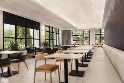 a restaurant with tables and chairs and windows at Radisson Hotel Seattle Airport in SeaTac