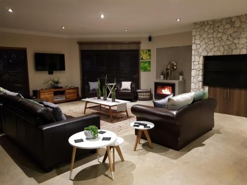 a living room with two leather couches and a fireplace at Vogelstrand Holiday House in Swakopmund