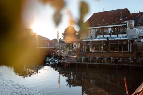 フラネケルにあるHotel Restaurant De Stadsherbergの川の景色を望む横にレストランがあります。