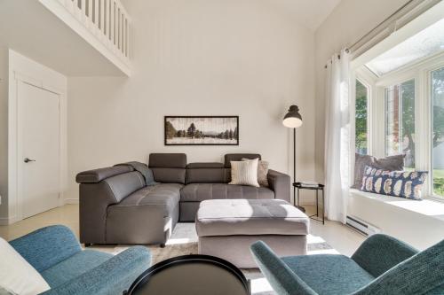 INITIAL - SYLVESTRE - Mont-Sainte-Anne في بوبريه: غرفة معيشة مع أريكة وكراسي