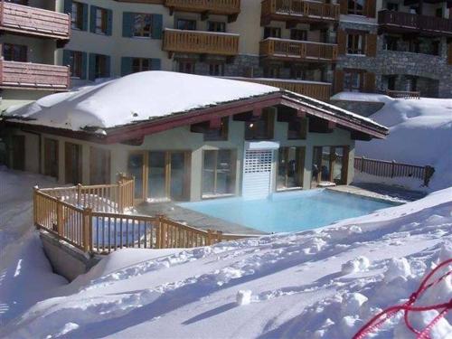 une maison avec une piscine dans la neige dans l'établissement ARC 1950 - APPT 2 CHAMBRES/ 1 COIN NUIT LUXUEUX- SKI AUX PIEDS, à Arc 1950