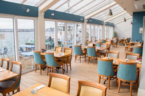 een restaurant met tafels en stoelen en het water bij WatersEdge Hotel in Cobh