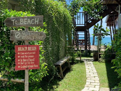 a sign for a beach with a bench in a garden at Sand in My Shoes Beach Loft in Thong Nai Pan Noi