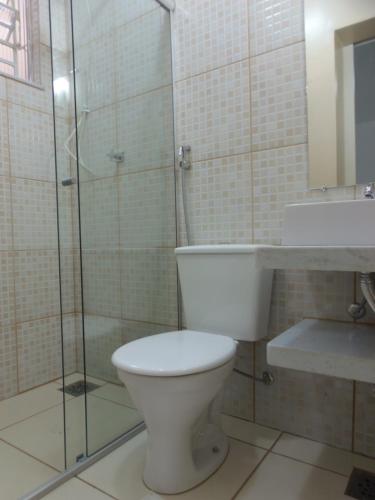 a bathroom with a toilet and a glass shower at Hotel Miranelli in Barbacena