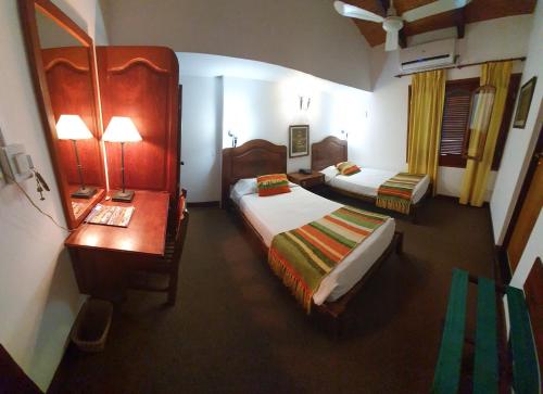 a hotel room with two beds and a desk and a bedroom at Hosteria-Spa Posada del Sol in Libertador General San Martín