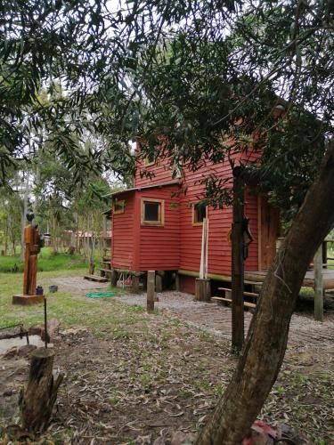 a red cabin in the middle of a forest at Ligustrum House in Punta Del Diablo