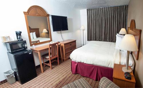 Express Inn & Suites في غرينفيل: غرفة في الفندق مع غرفة نوم مع سرير ومكتب
