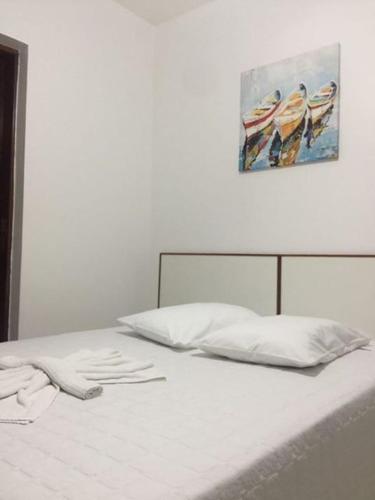 a bed with white sheets and a painting on the wall at Hotel Miranelli in Barbacena