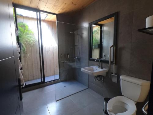 a bathroom with a toilet and a sink and a window at Hotel Puerto Viejo Llico in Llico
