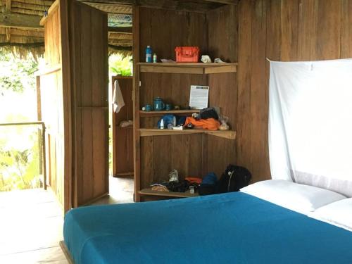 a bedroom with a blue bed and wooden walls at Punta Brava in Nuquí