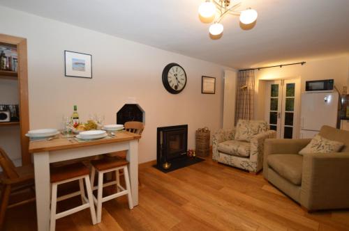 a living room with a table and a clock on the wall at Newton Cottage South in Inveraray
