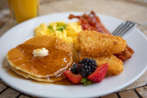 Un plato blanco de comida de desayuno con panqueques y fruta. en Floridays Orlando Two & Three Bed Rooms Condo Resort, en Orlando